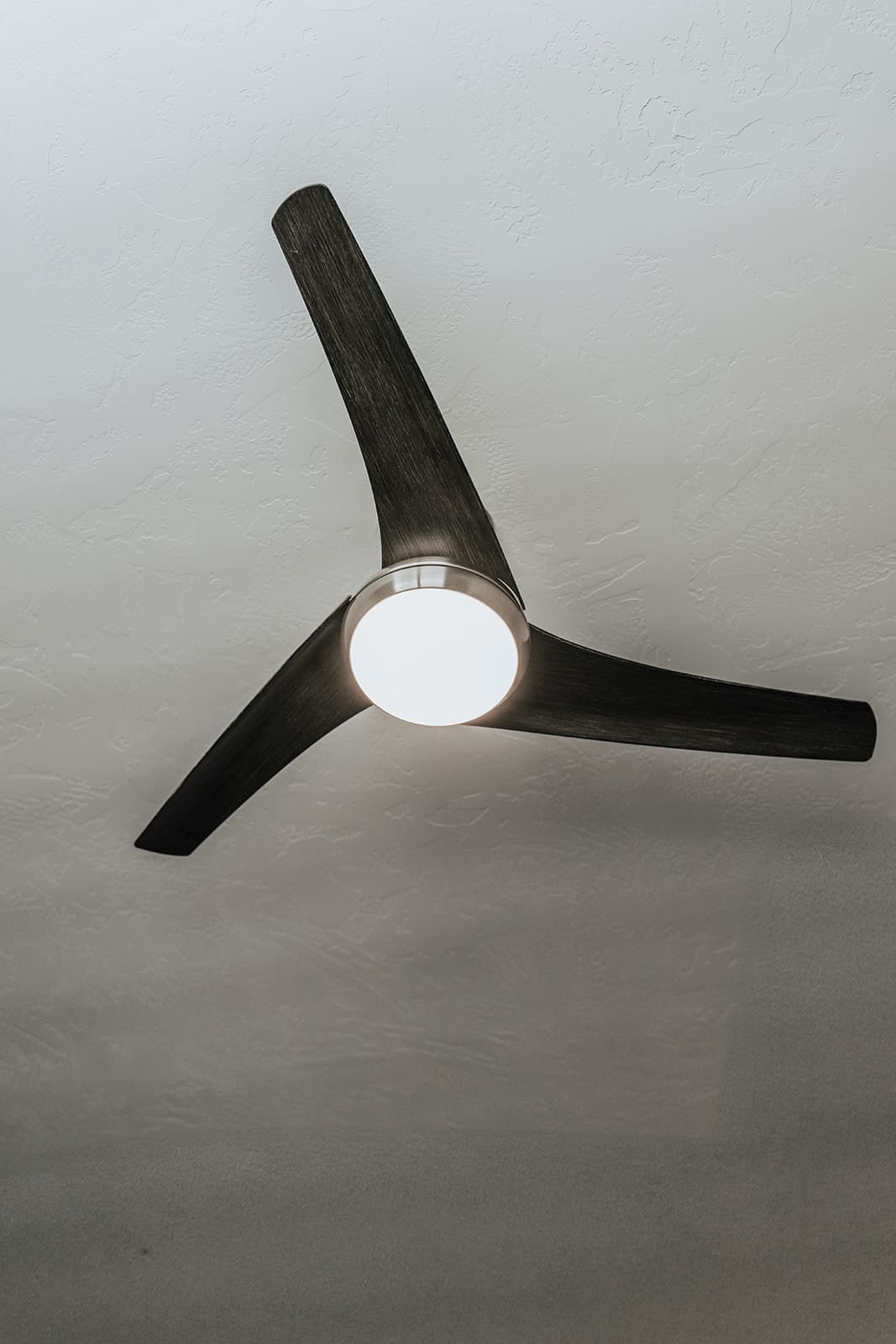 A modern three blade ceiling fan with light kit, installed and balanced